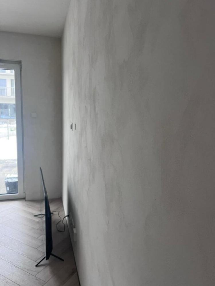 Applying limewash with brush on a clean prepared surface in thin layers